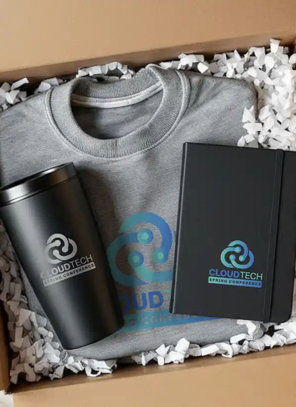 Branded gift box containing a sweatshirt, notebook, and insulated travel tumbler with conference logo.