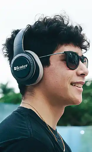 Person wearing over-ear headphones and sunglasses in an outdoor setting.