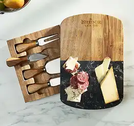 Wooden cheese board with assorted cheeses and salami beside a matching knife set in a storage tray.