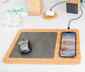 Wood desk organizer with mouse pad and built-in wireless charging area holding a smartphone and computer mouse.