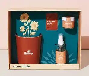 Branded gift box with a small potted plant, seed packet, candle, and spray bottle arranged inside.